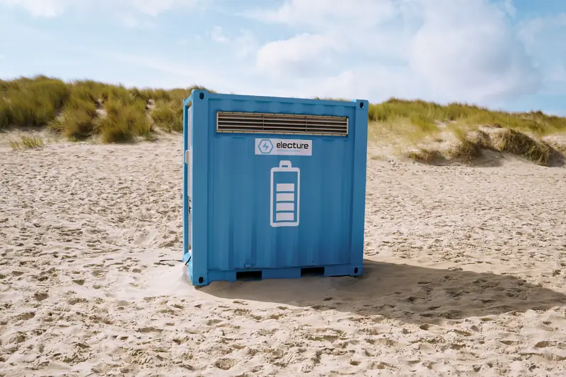 Een batterijcontainer in het zand tussen de duinen